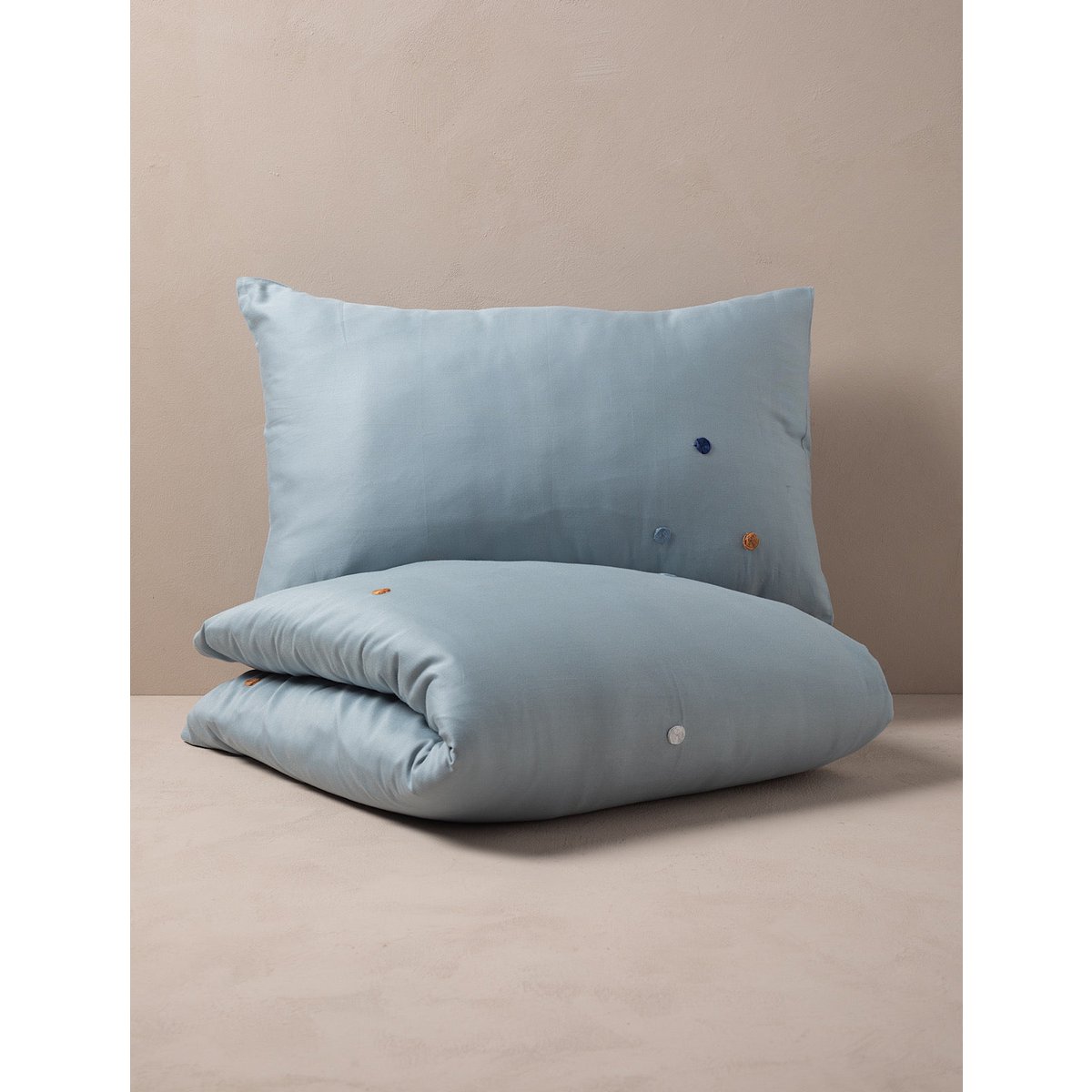 Light blue pillow and duvet set on a beige surface with a beige background