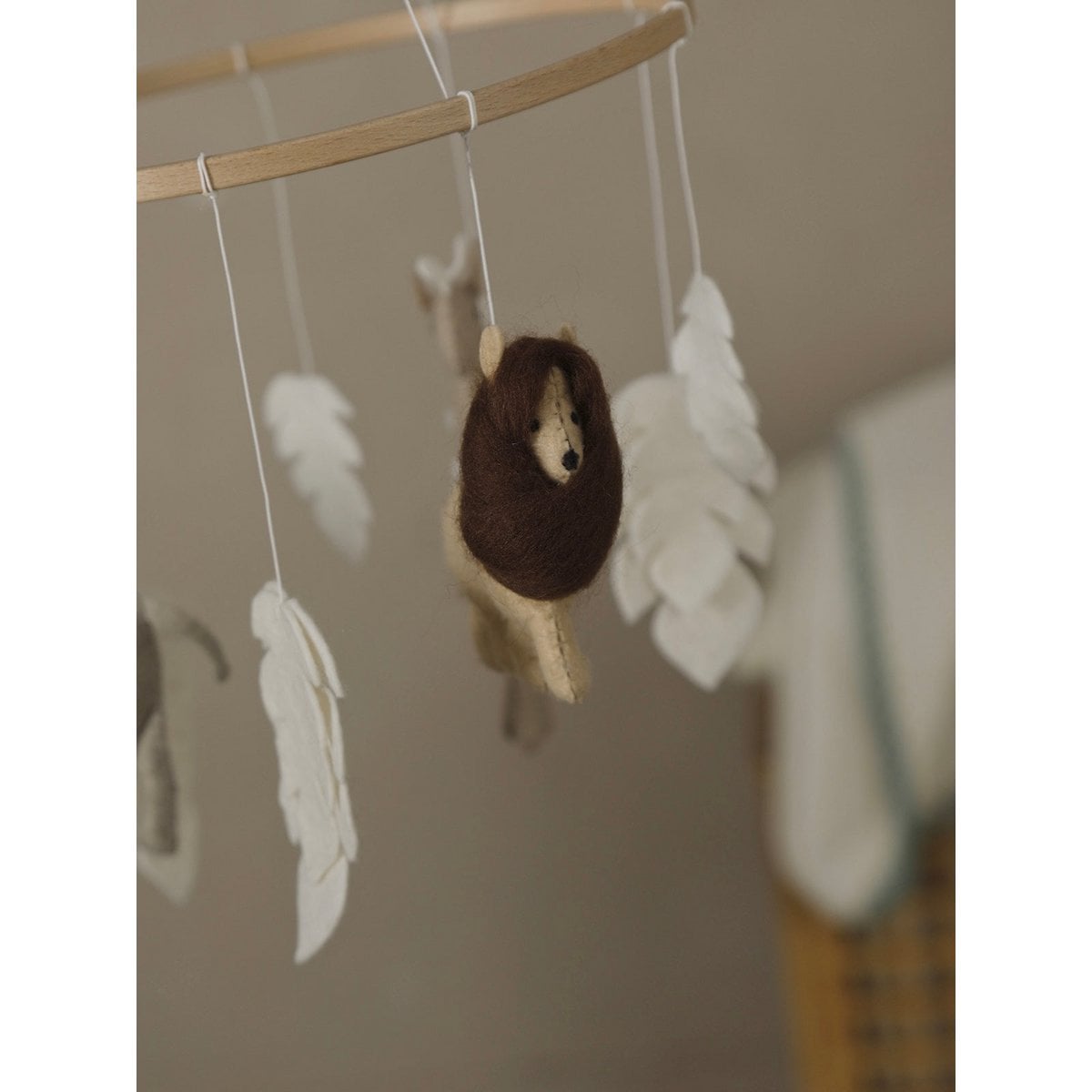Hedgehog toy hanging from a string with feathers against a neutral background