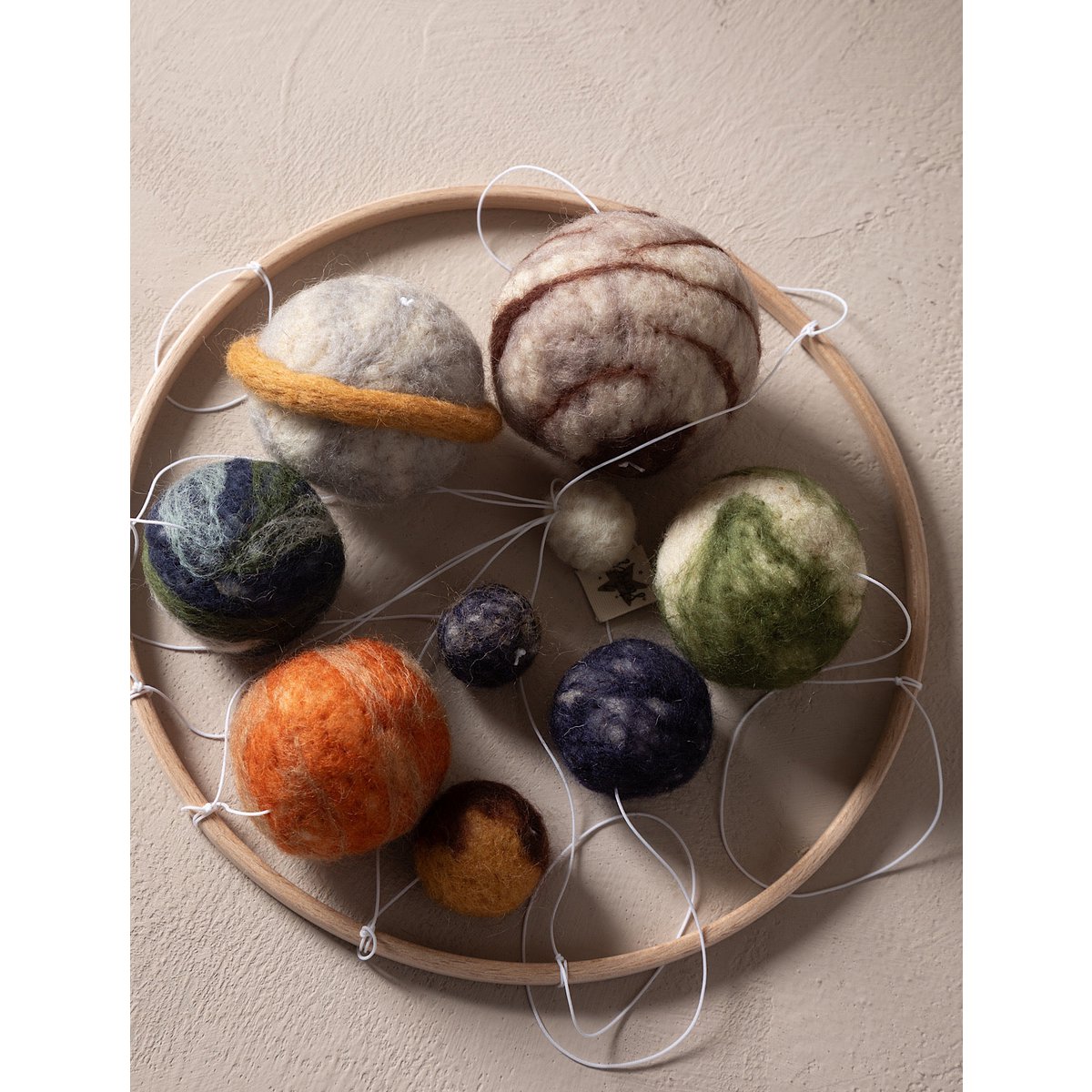 Wooden embroidery hoop with felted balls of various colors on a beige background