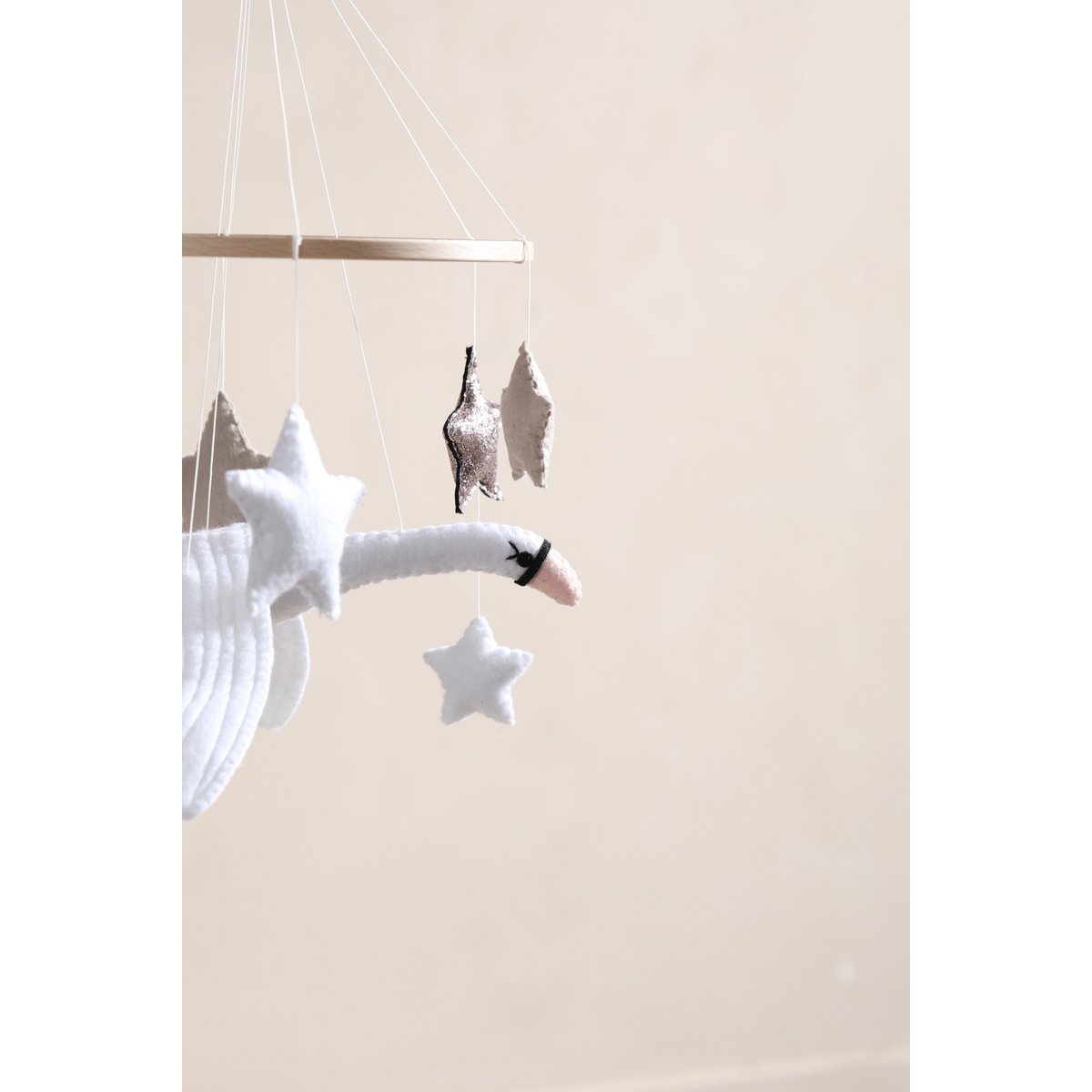 Decorative mobile with birds and stars hanging from a string against a beige background