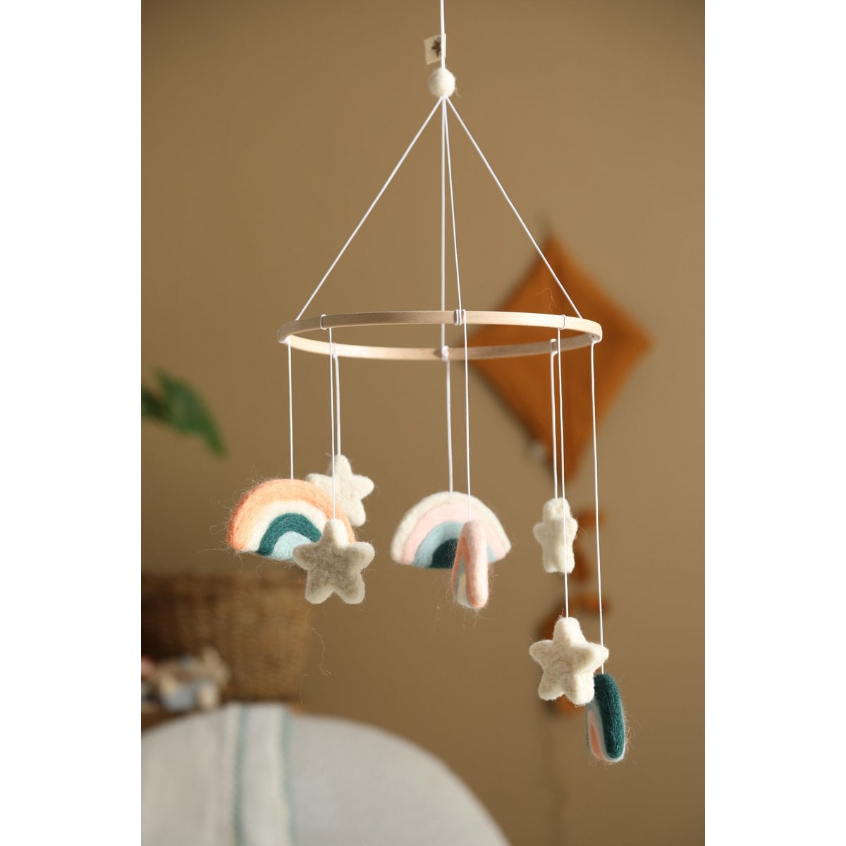Hanging mobile with rainbow and star shapes against a neutral background
