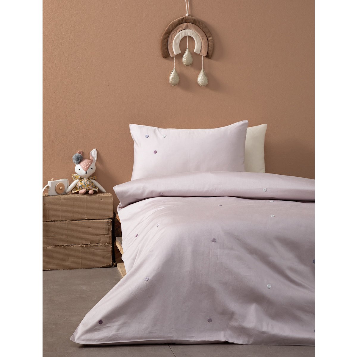 Children's bedroom with pink bedding, toy, and decorative wall hanging on a brown wall.
