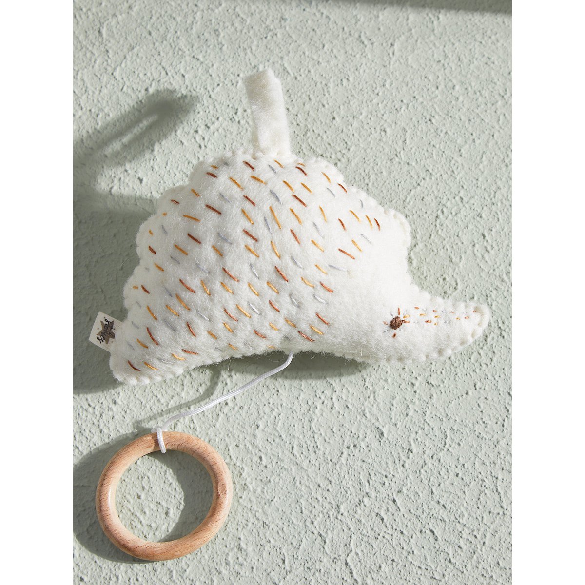 White textured toy with wooden ring on a light gray background