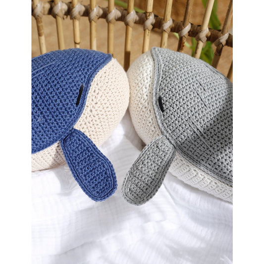 Two crocheted dolphins, one blue and one gray, on a white surface with a woven background.
