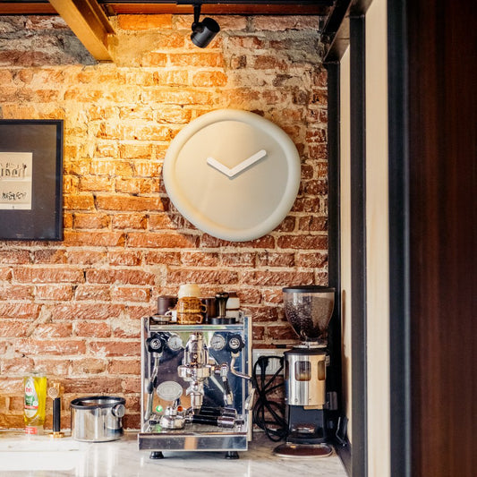 Coffee-making equipment on a counter with a clock on the wall in a cozy setting.