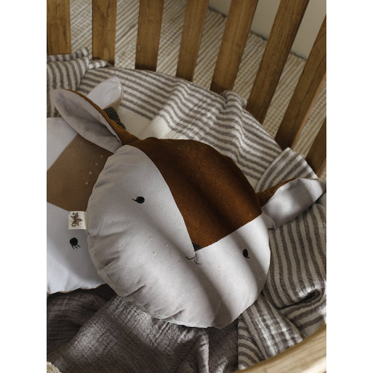 Plush toy cow in a crib with striped bedding