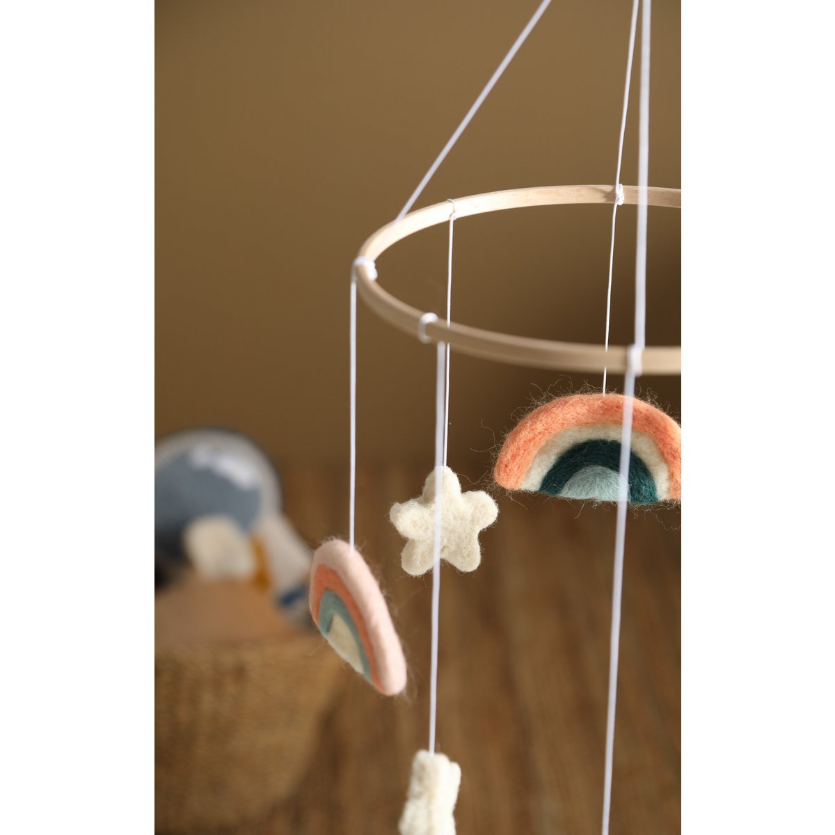 Decorative mobile with rainbow and star shapes hanging against a brown background