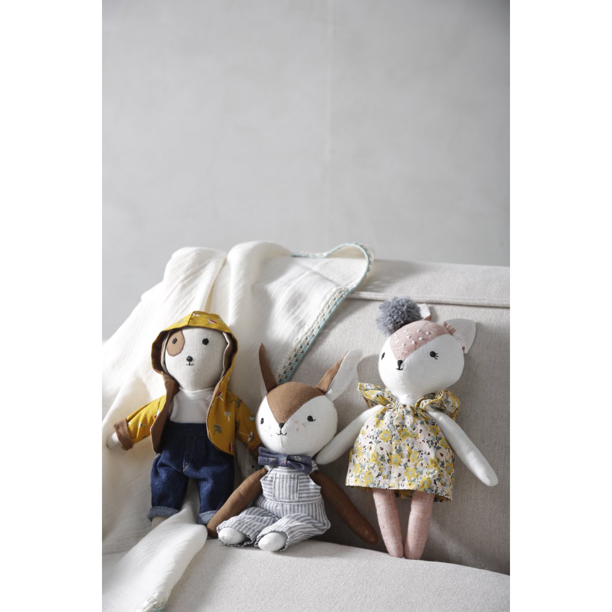 Three stuffed animals on a light-colored couch with a neutral background