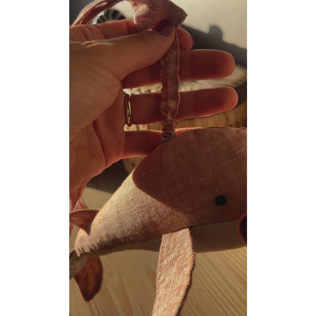 Small brown plush toy held in a hand with a blurred background