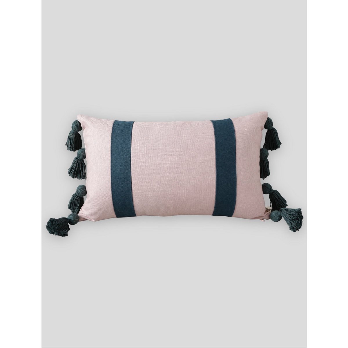 Pink pillow with navy stripes and tassels on a light gray background
