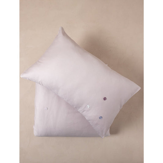 White pillow with decorative buttons on a beige background