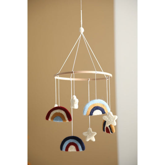 Decorative mobile with rainbow and star shapes hanging against a beige wall.