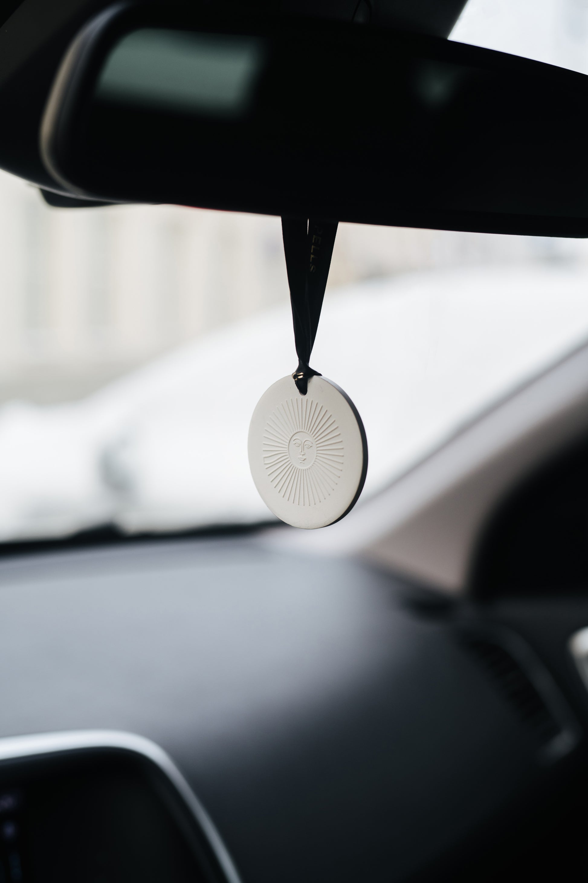 Car air freshener hanging from the rearview mirror with a blurred background