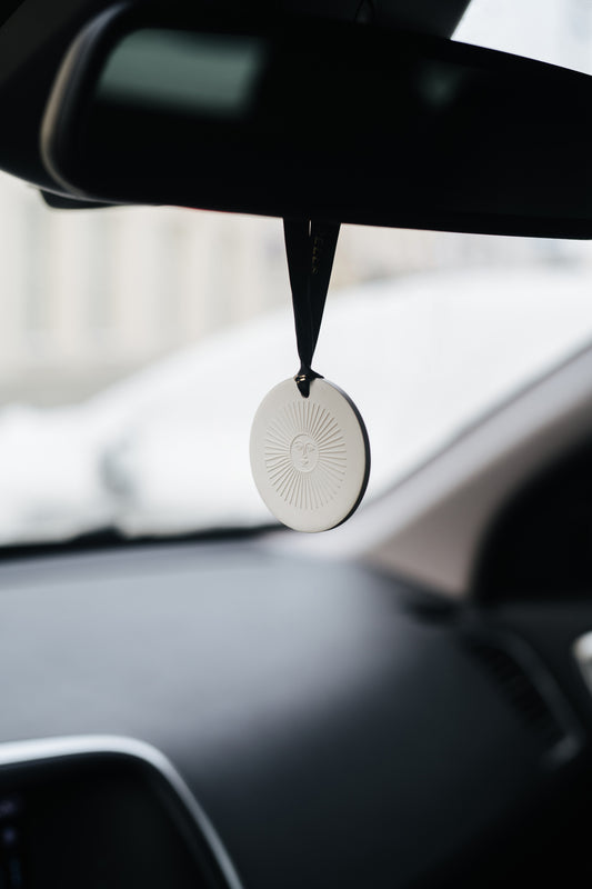 Car air freshener hanging from the rearview mirror with a blurred background