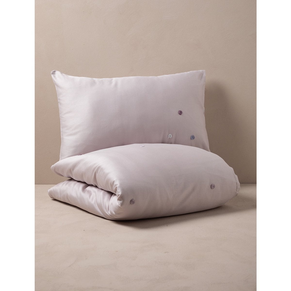 White pillow and duvet set on a beige surface with a neutral background