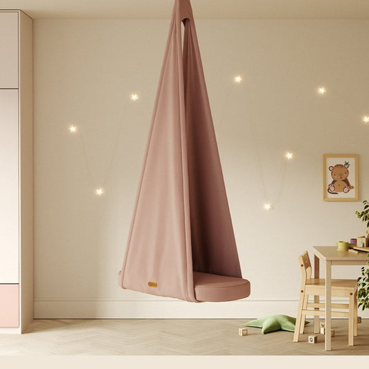 Pink hanging chair in a room with a table and chair, and a framed picture on the wall.