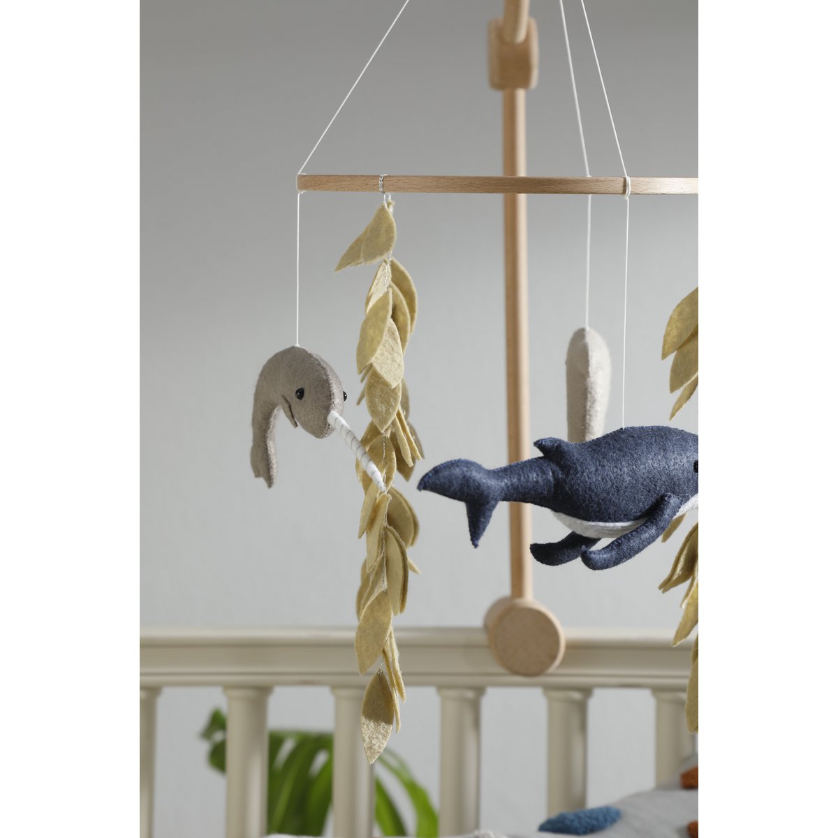 Decorative mobile with whale and leaf designs hanging from a wooden stand.