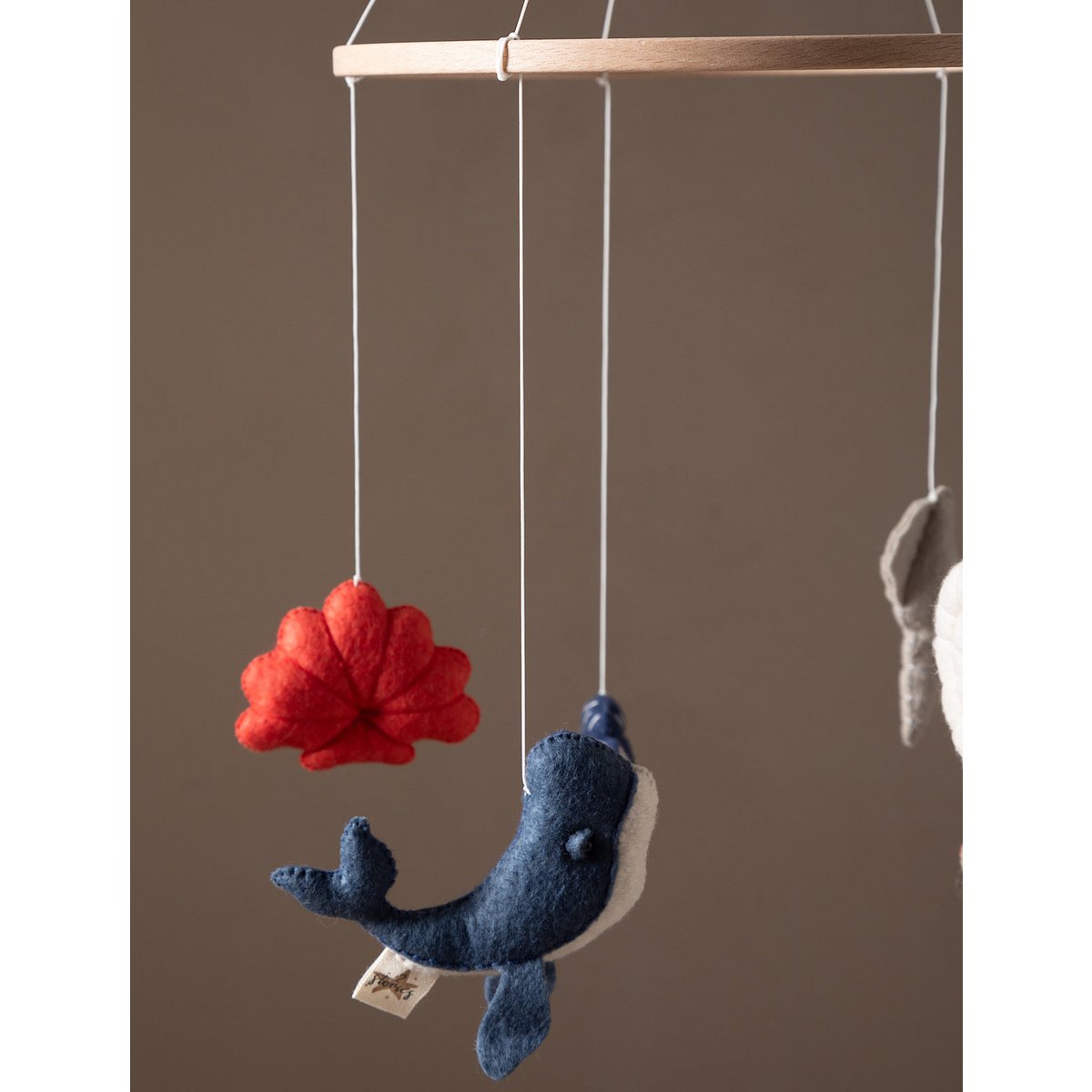 Felt whale and red flower mobile against a brown background