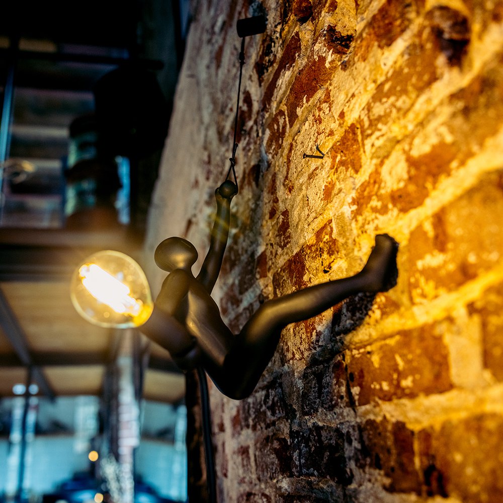 Decorative wall light fixture with a glowing bulb against a brick wall.