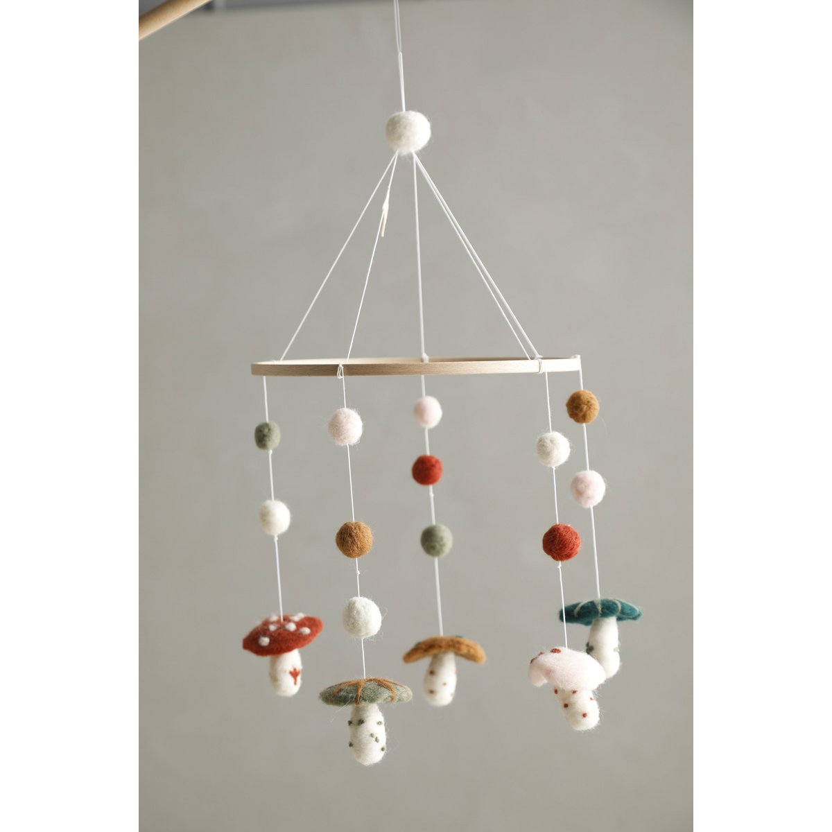 Colorful mushroom-shaped mobile hanging against a plain background