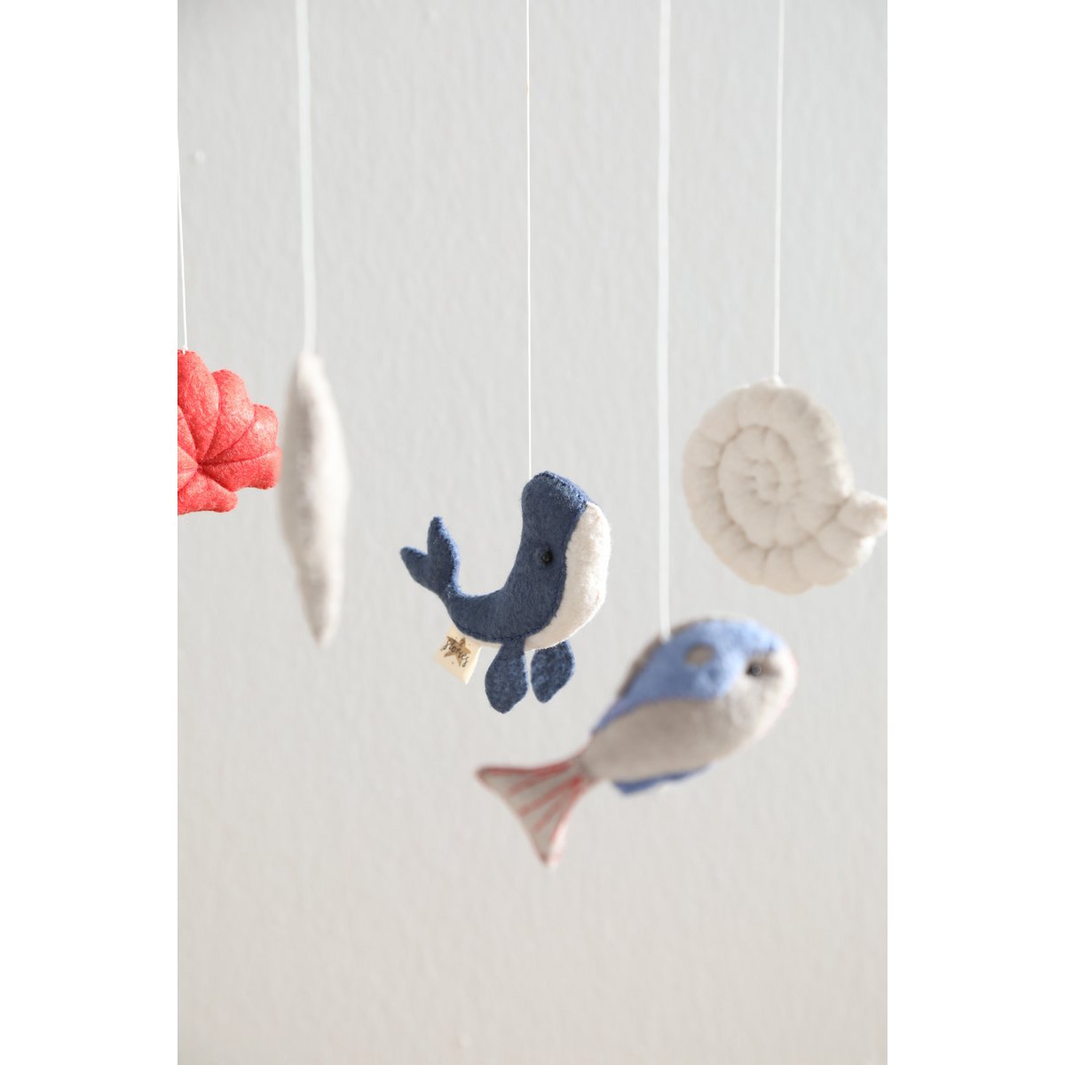 Decorative mobile with fish and shell shapes on a white background