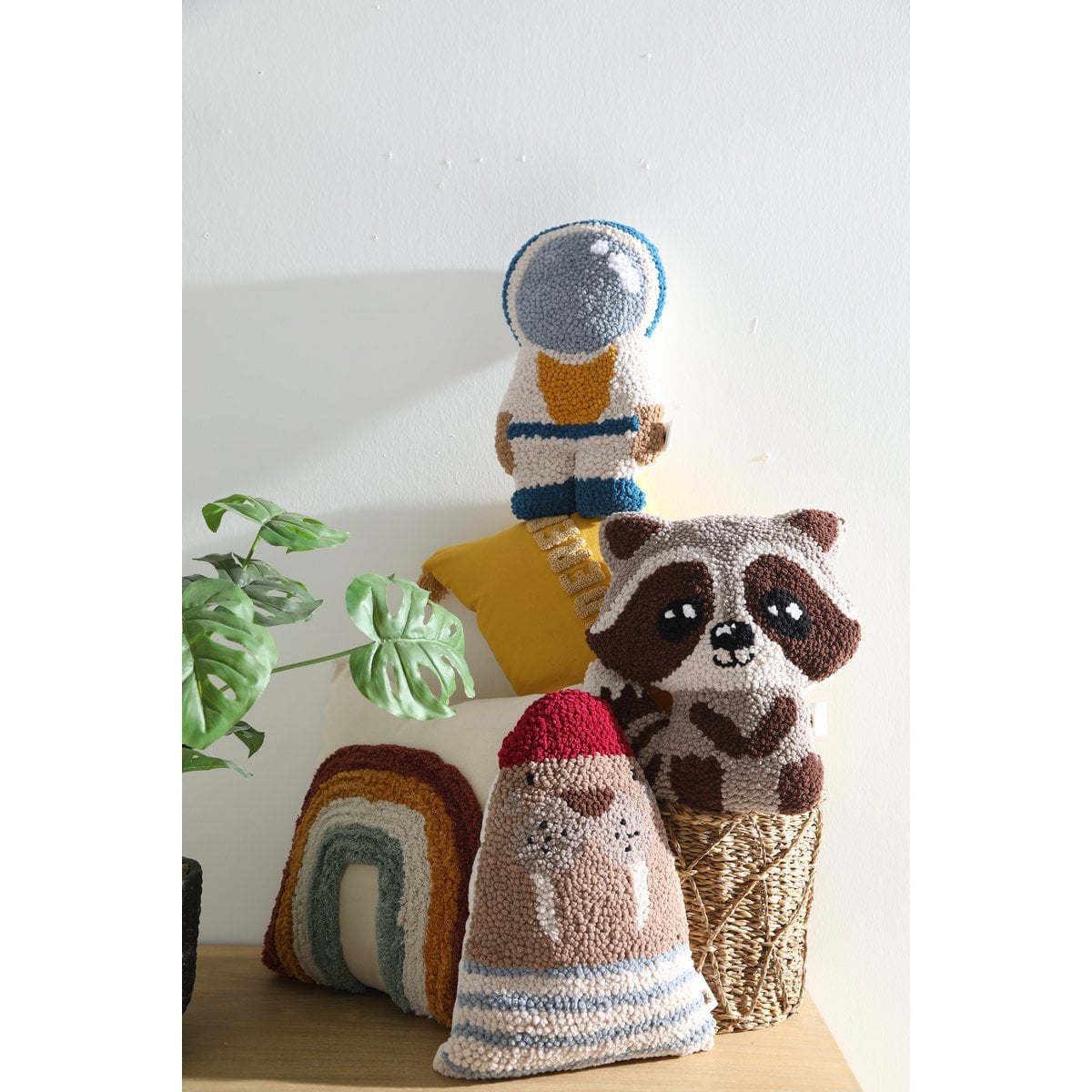 Knitted toys including a raccoon, astronaut, and rainbow design on a light background.