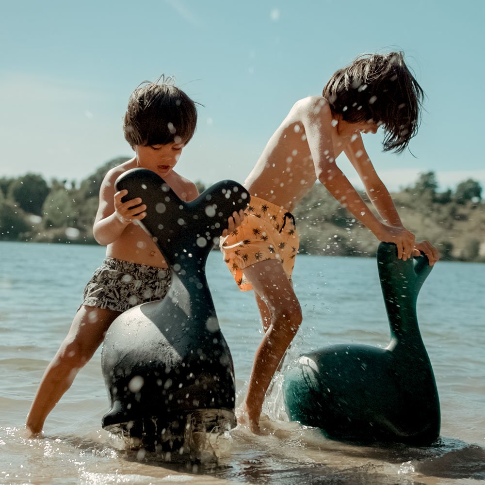 Two children playing in water with inflatable animals on a sunny day.
