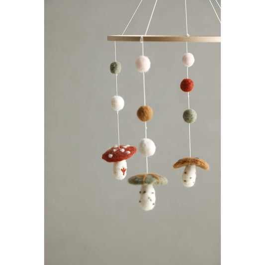 Decorative mobile with mushroom-shaped objects hanging from a wooden rod against a plain background.