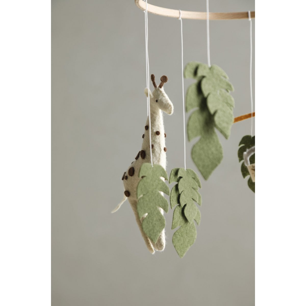 Giraffe and leaf mobile hanging against a neutral background