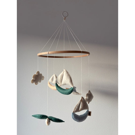 Decorative hanging mobile with sailboats and flowers on a plain background