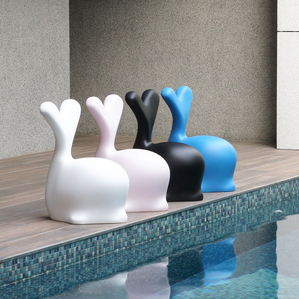 Five colorful whale-shaped stools by a poolside.