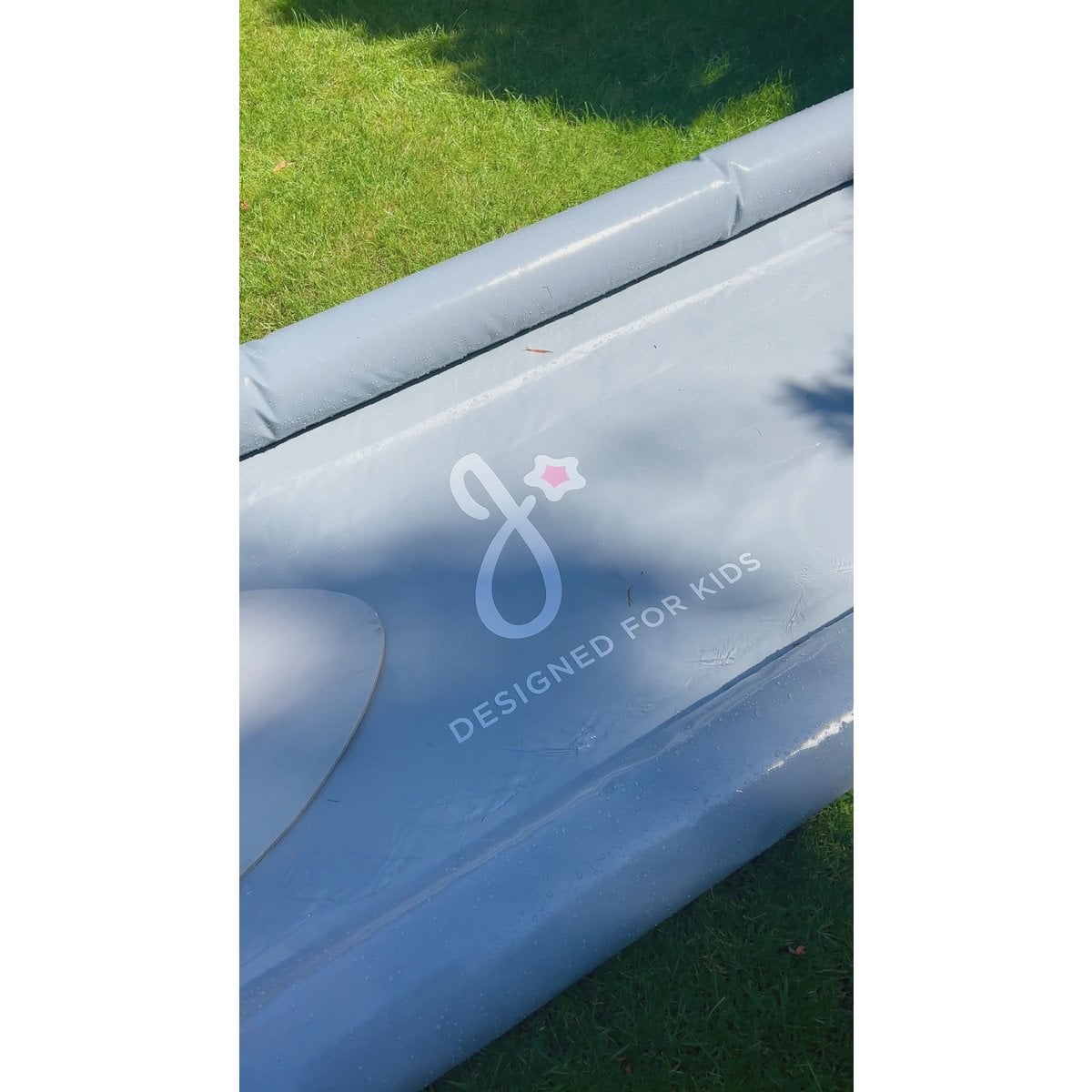 Inflatable pool with 'Designed for Kids' logo on a grassy background