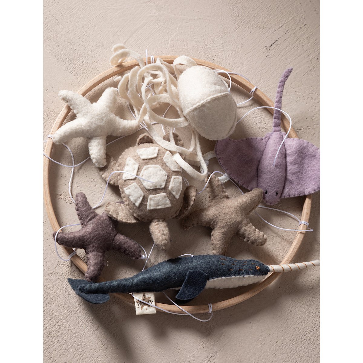 Collection of soft toy animals on a wooden tray against a beige wall.
