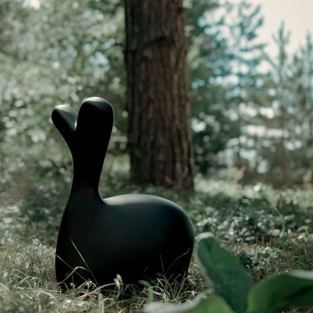 Black whale sculpture in a natural setting with trees and grass.