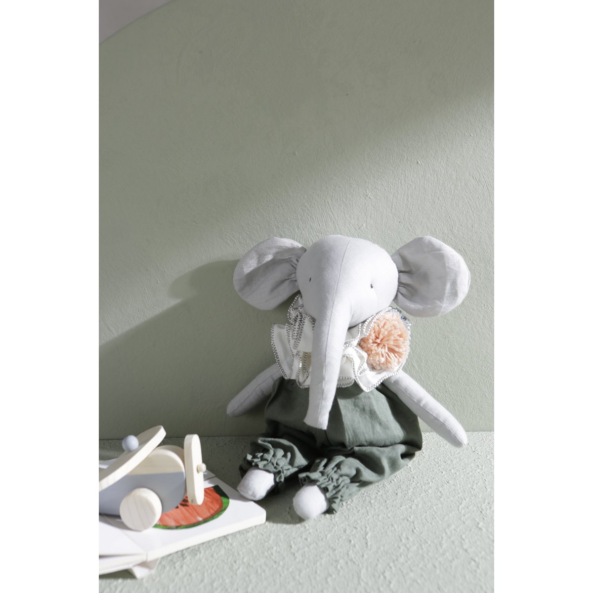 Plush elephant toy with a flower on a light surface against a plain background