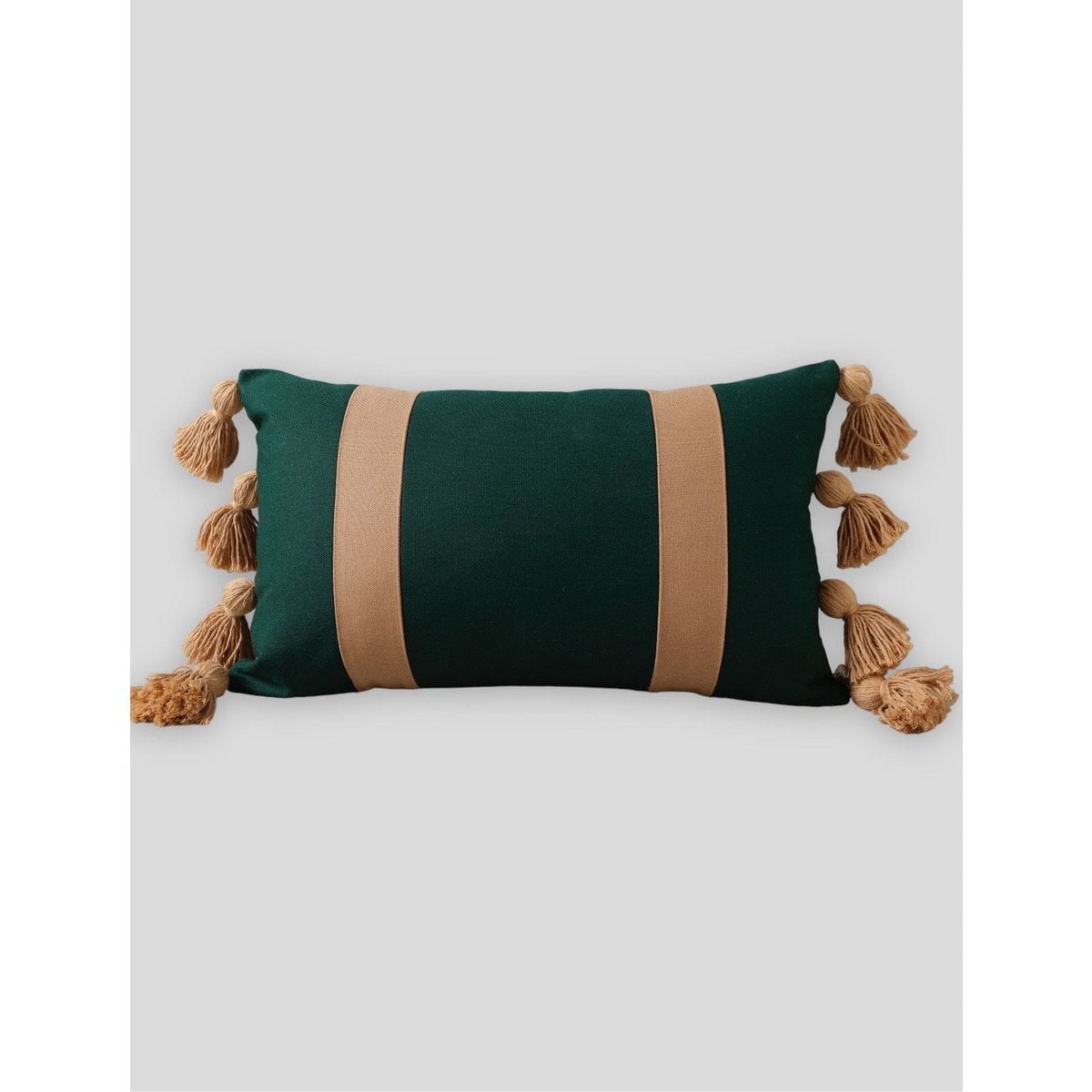 Green and beige striped pillow with tassels on a light gray background