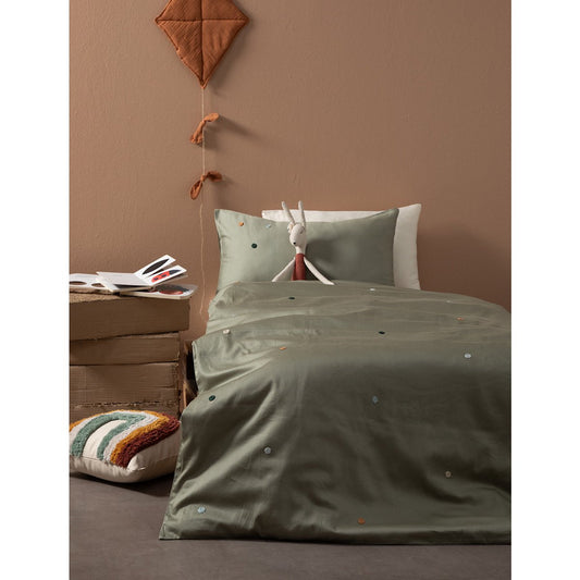 Bed with green bedding and a brown wall in the background