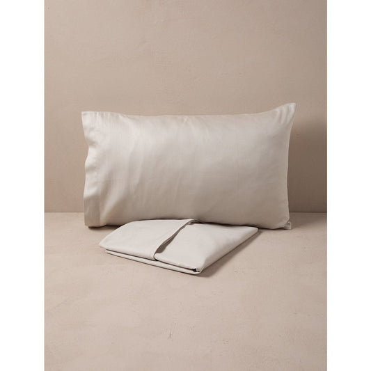 Beige pillow and folded blanket on a beige surface with a neutral background