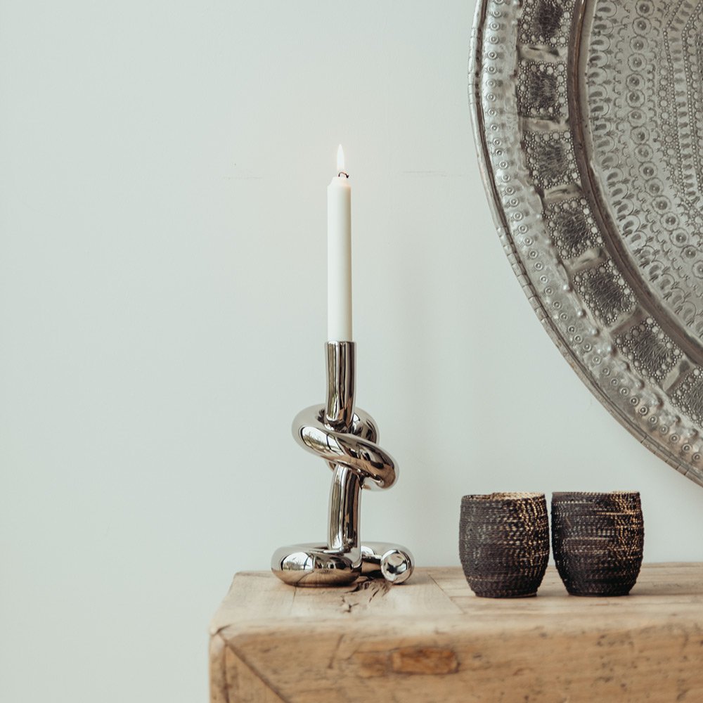 Decorative candle holder with a candle, two small textured containers, and a decorative mirror on a wooden surface.