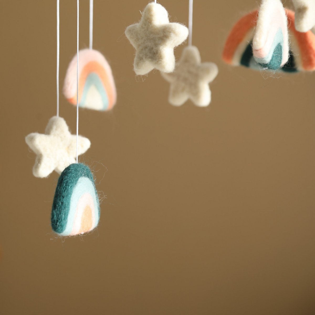 Felt decorations shaped like stars and rainbows hanging against a brown background