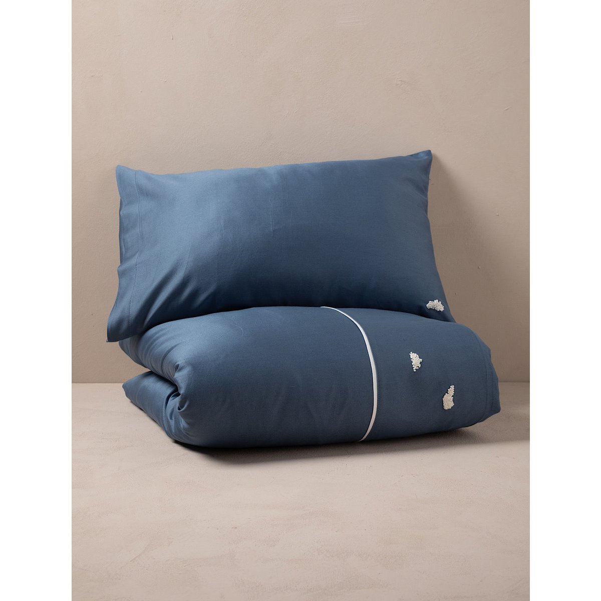 Blue bedding set with embroidered designs on a beige surface