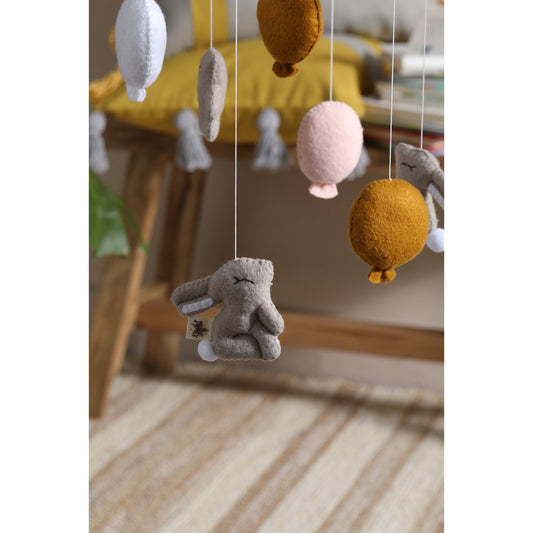 Felted toy animal mobile with colorful hanging elements in a home setting