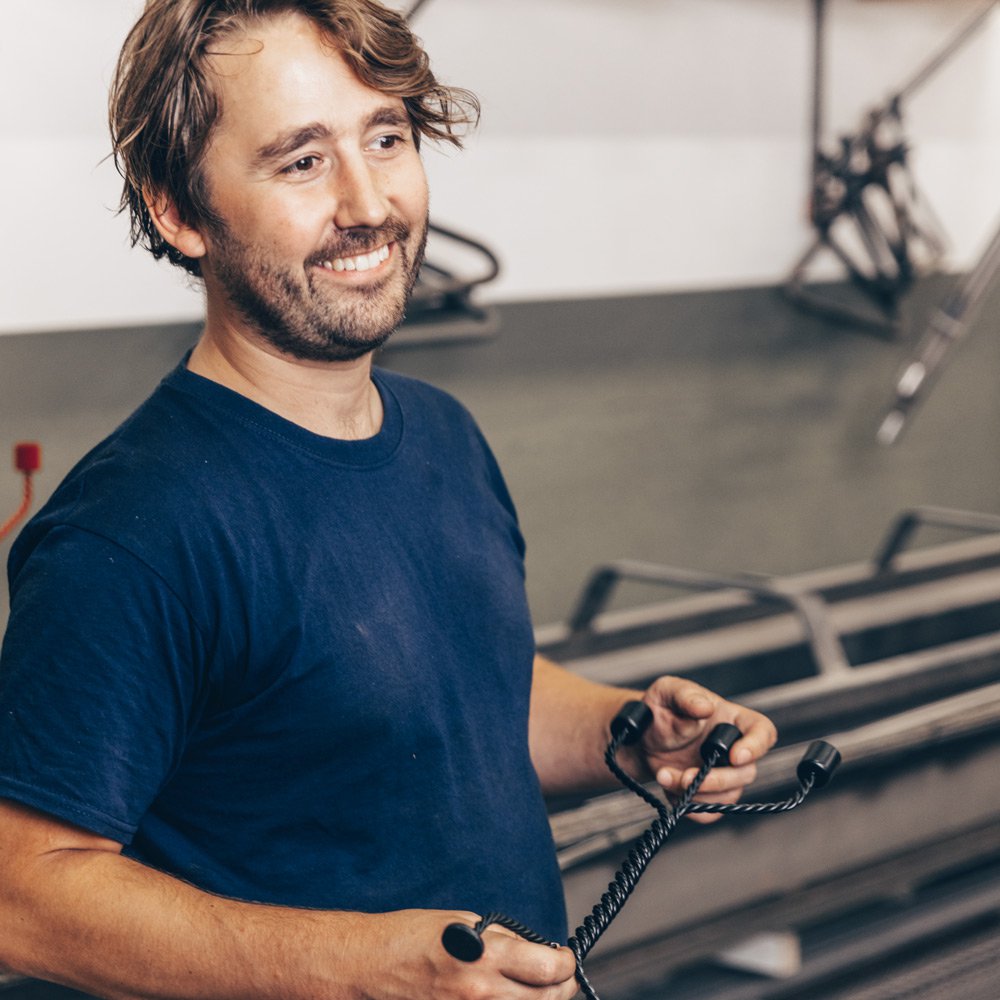 Ward Wijnant holding a tool in front of a vehicle in a garage