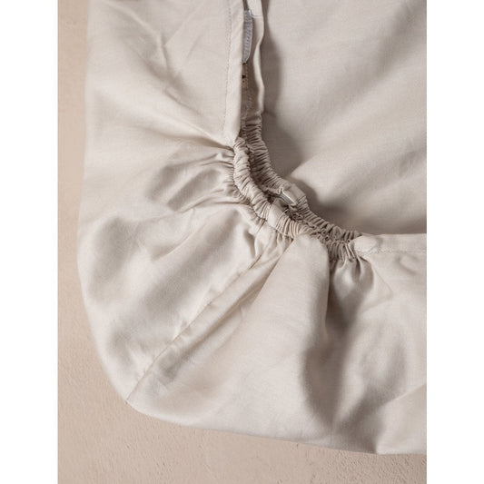 Close-up of a fitted sheet on a bed with a neutral background