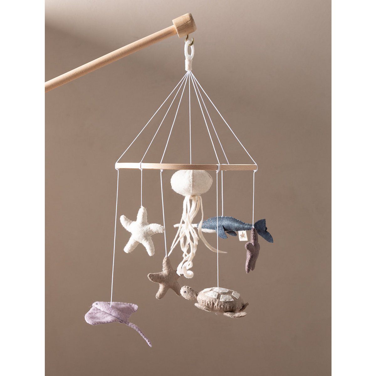 Hanging mobile with sea-themed toys on a beige background
