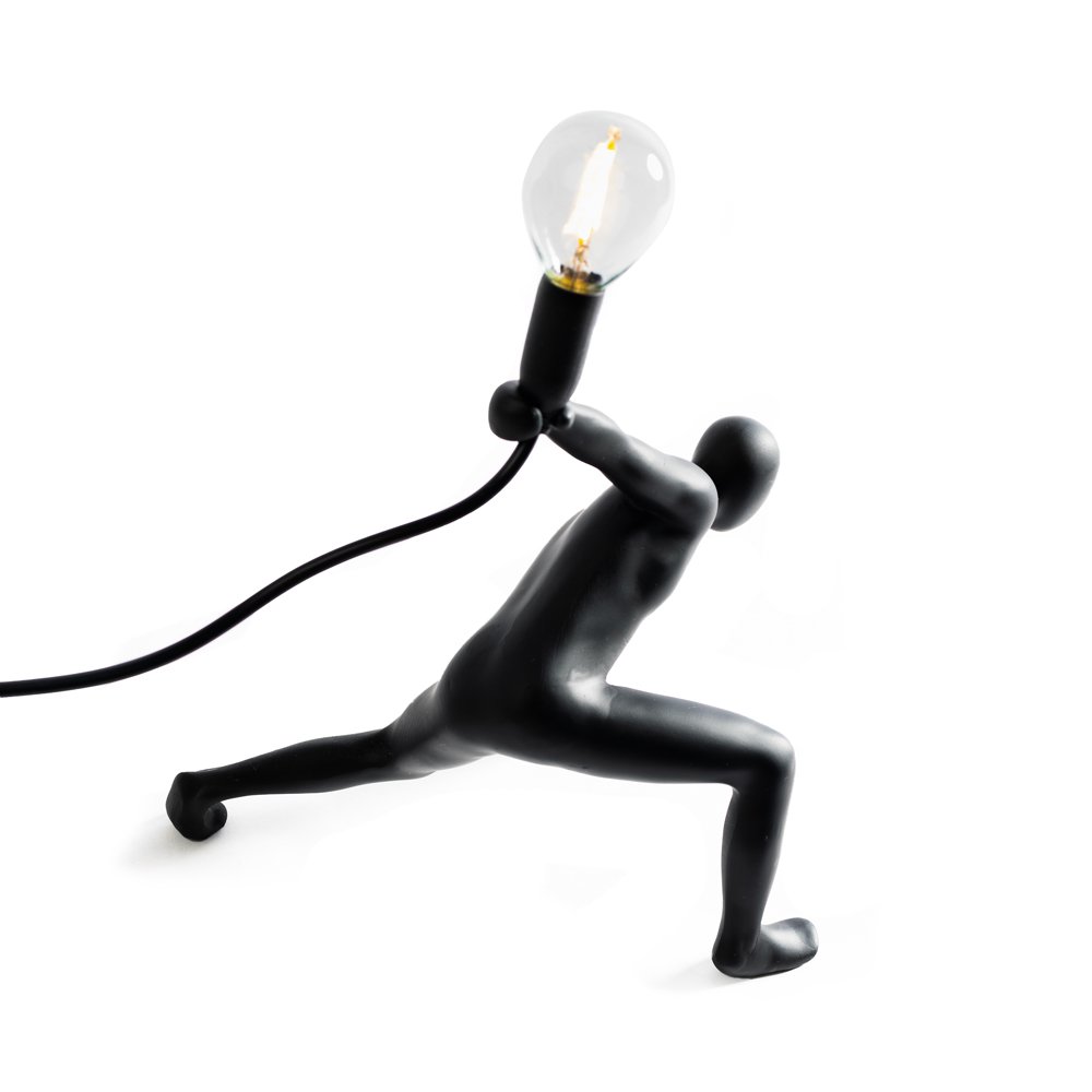 Black sculpture of a person holding a light bulb on a white background