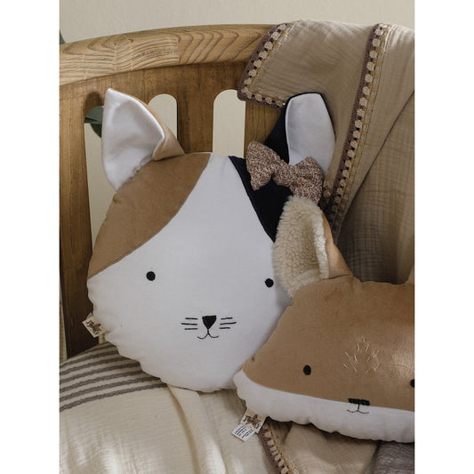 Cat-shaped pillow with a bow tie on a wooden surface