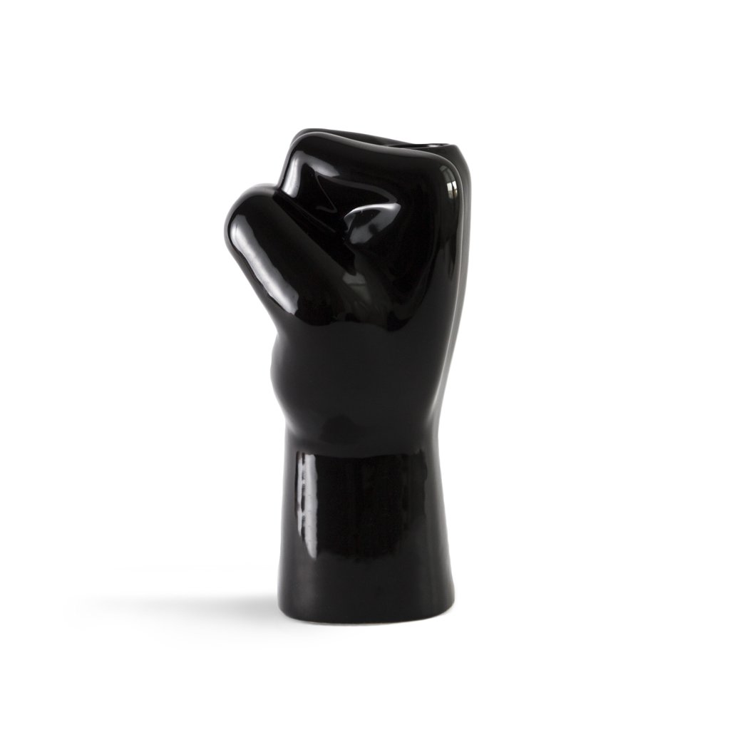 Black ceramic sculpture of a fist on a white background