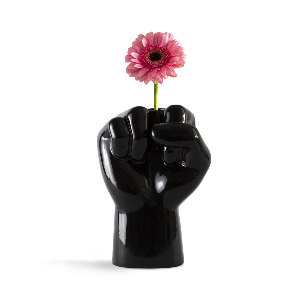 Black fist-shaped vase with a pink flower on a white background