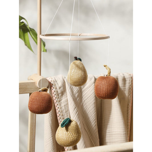 Knitted pumpkin decorations hanging from a mobile against a neutral background